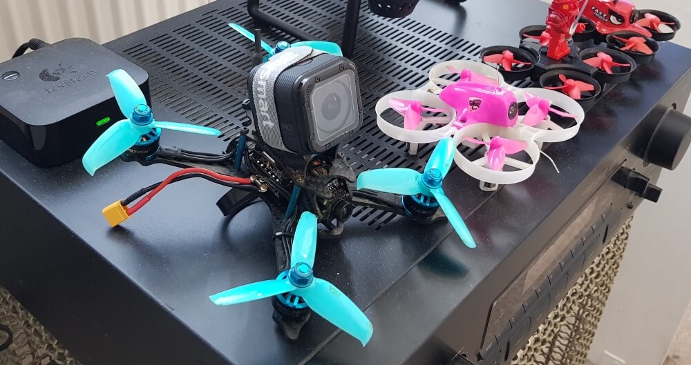 A drone with GoPro on top aligned with several other small drones 