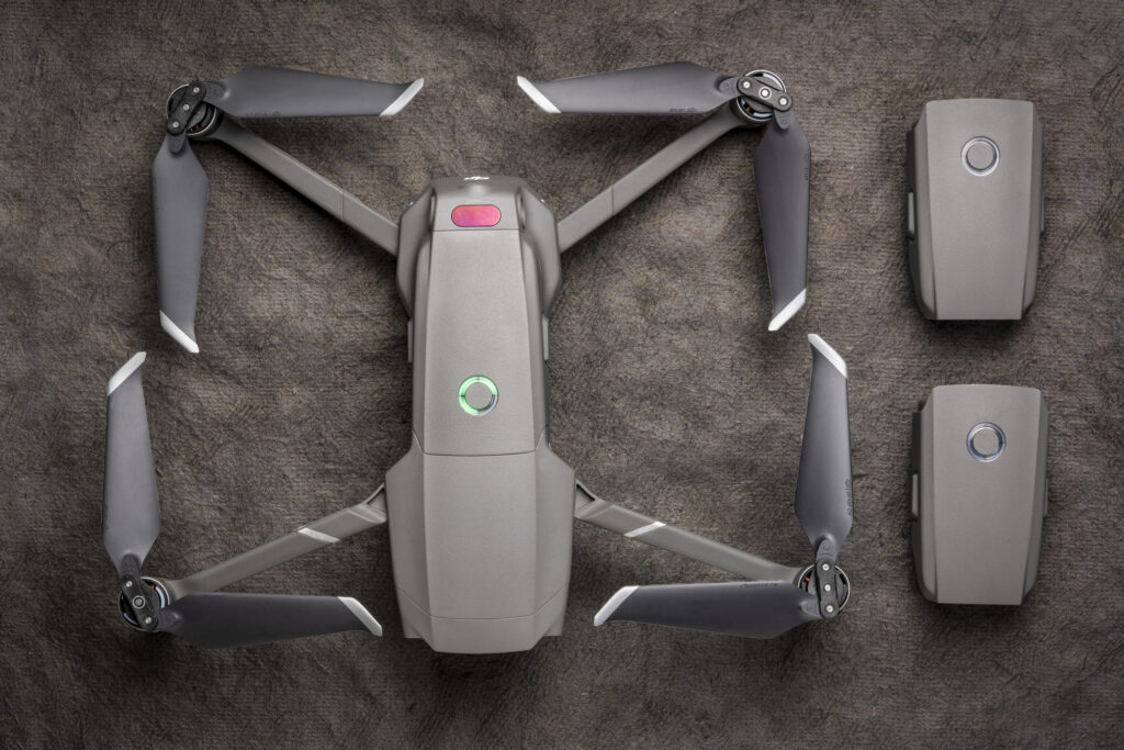 Overhead view of DJI Mavic 2 pro drone with two spare batteries against textured handmade paper.